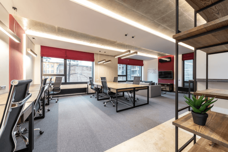 An image of an office with chairs and a table with white walls and red curtains