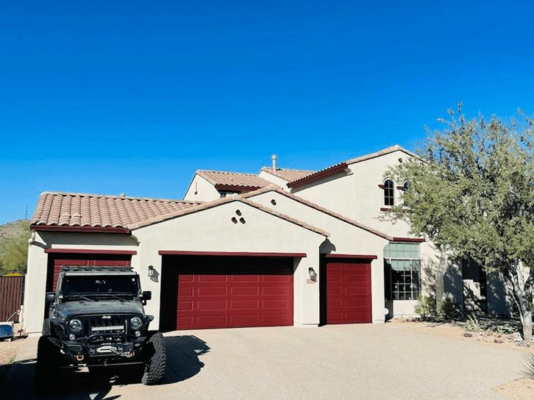 A newly painted dark-colored garage door with a jeep parked outside