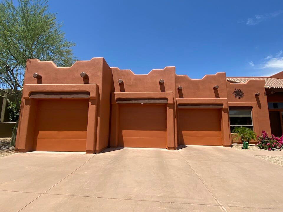 Three garage doors of a property painted in a brownish shade