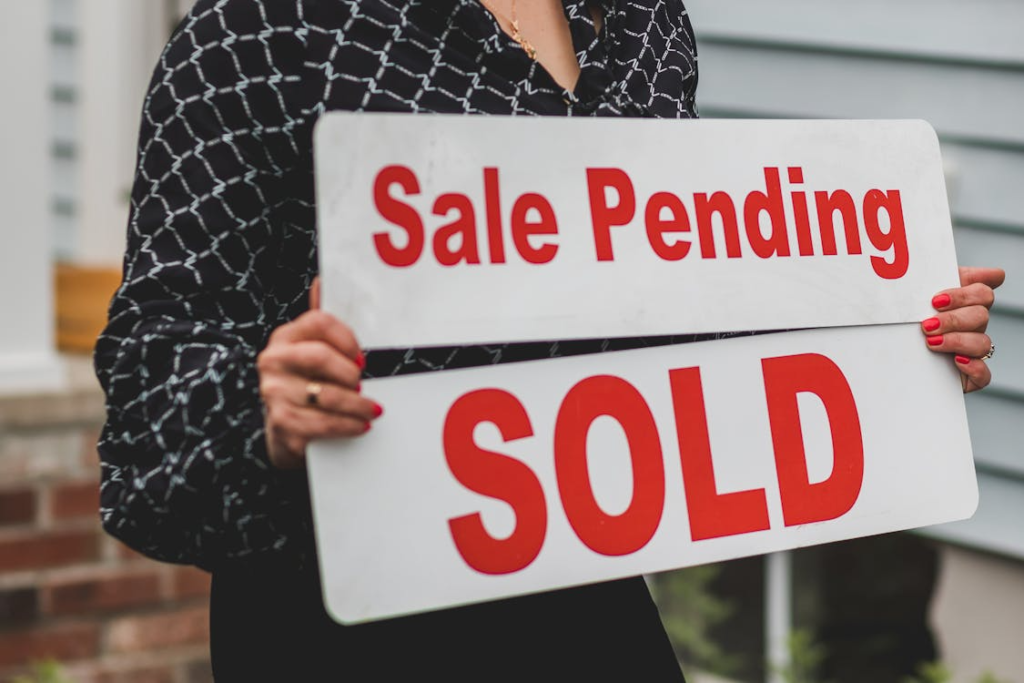 A person holding a sale pending and sold sign