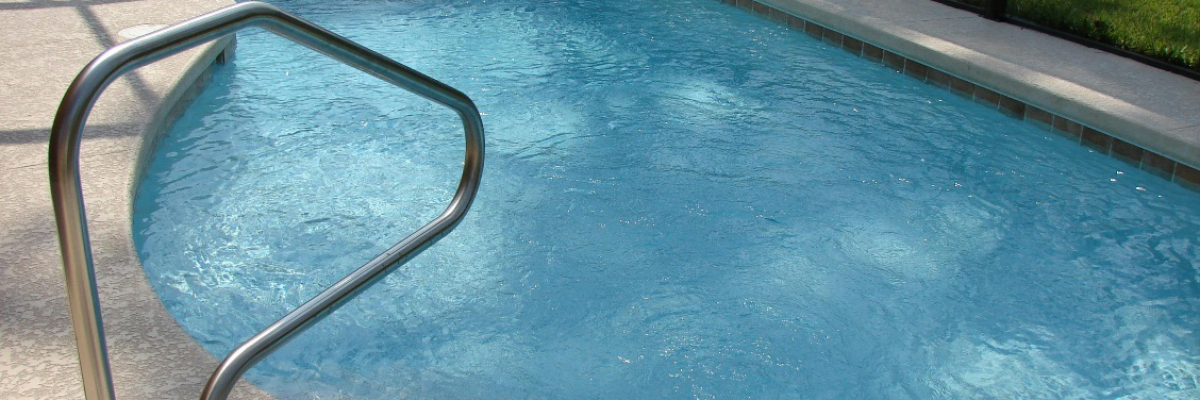An image of a clear swimming pool with a concrete pool deck