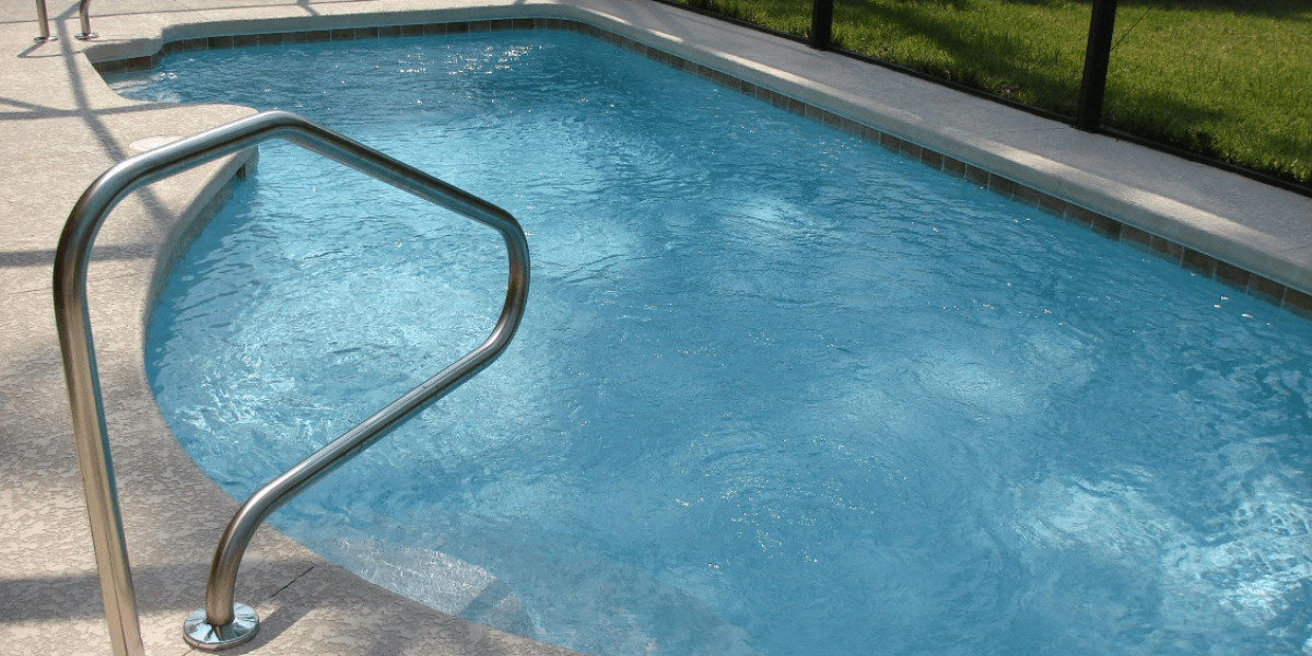An image of a clear swimming pool with a concrete pool deck