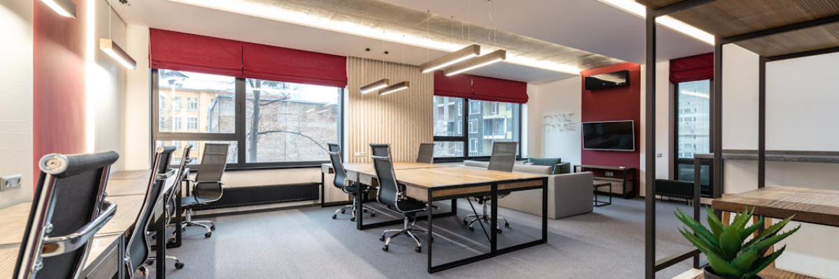 An image of an office with chairs and a table with white walls and red curtains
