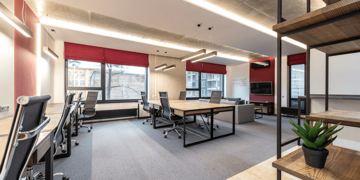 An image of an office with chairs and a table with white walls and red curtains